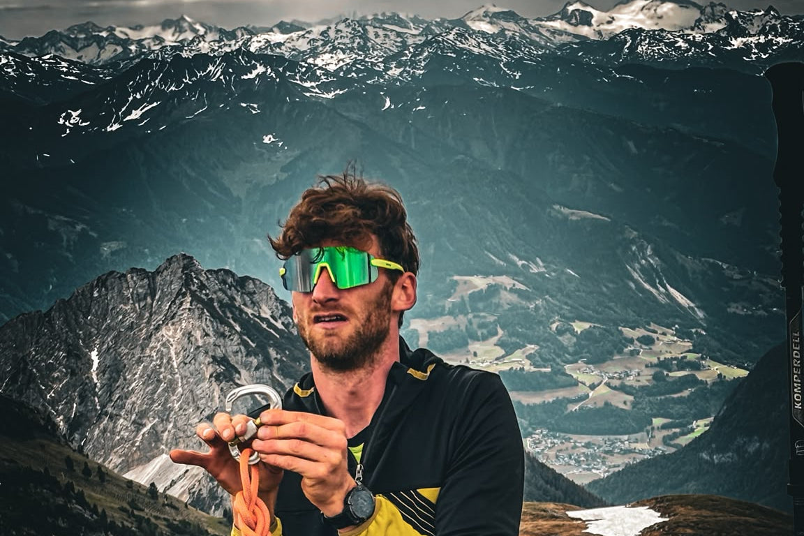 VanUtz mit Seil und Karabiner vor Bergpanorama, mit Blacksheep RACE by Silvio neon